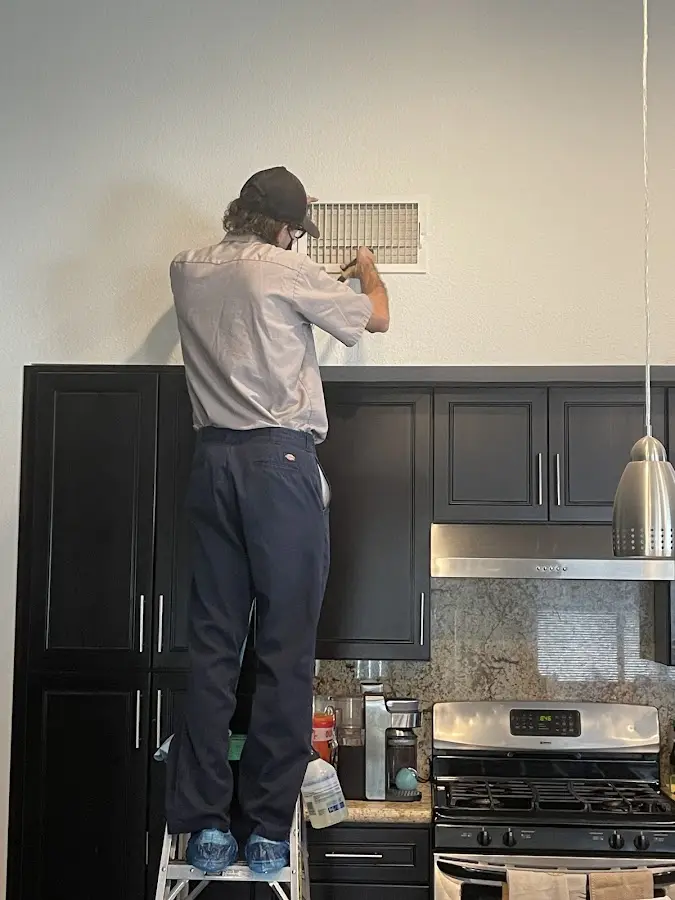 Technician inspecting an air vent during HVAC service in Cedar Mill